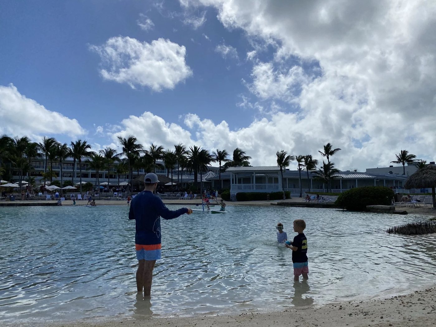A family wading in the shallows at a resort lagoon